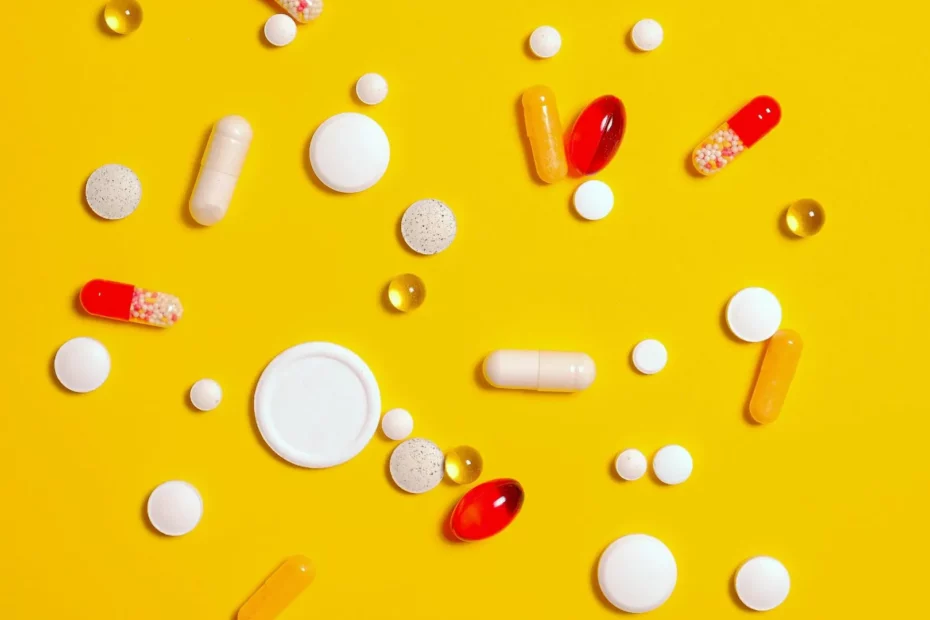 Les compléments alimentaires : assortiment de gélules, comprimés et capsules multicolores dispersés sur un fond jaune, représentant divers types de suppléments nutritionnels.